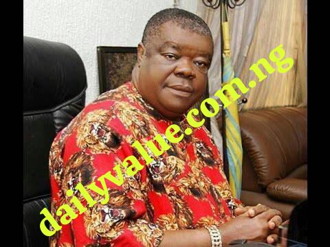 Rev. Dr. Uma Ukpai seated in a formal office setting, wearing a red traditional outfit with lion head patterns, symbolizing strength and cultural pride.
